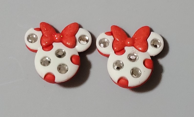 May include: Two red and white Minnie Mouse head-shaped buttons with rhinestones.