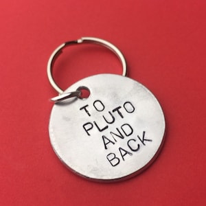 May include: Silver key chain with a round tag that says "To Pluto and Back".