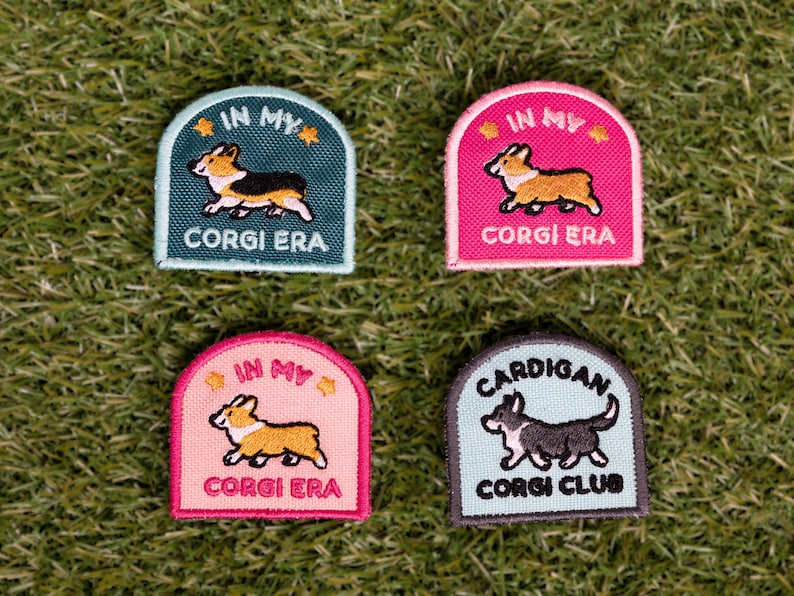 May include: Four embroidered patches featuring corgis. Two patches are pink with the text "In My Corgi Era" and a cartoon corgi. One patch is teal with the text "In My Corgi Era" and a cartoon corgi. One patch is light blue with the text "Cardigan Corgi Club" and a cartoon corgi.