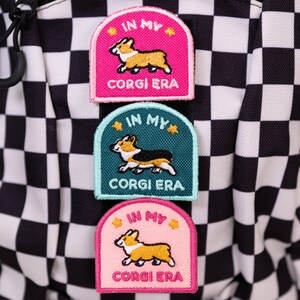 May include: Three embroidered patches with a cartoon corgi dog and the text "In My Corgi Era" in pink, teal, and light pink.
