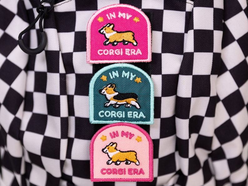 May include: Three embroidered patches with a cartoon corgi dog and the text "In My Corgi Era" in pink, teal, and light pink.