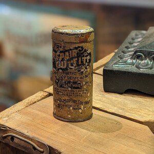 Puede incluir: Un contenedor de hojalata vintage para un kit de reparaci&oacute;n de neum&aacute;ticos. La lata est&aacute; etiquetada como "Free Repair Outfit" y "For the Dunlop Detachable Single Tube Tires". La lata est&aacute; hecha por la American Dunlop Tire Company en la ciudad de Nueva York.