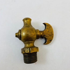 May include: Antique brass faucet with a T-shaped handle. The faucet has a threaded end for connecting to a pipe.