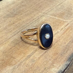 Peut inclure: Bague dor&eacute;e orn&eacute;e d'une pierre ovale bleu fonc&eacute; avec un petit accent blanc rond. La bague a un design &agrave; anneau fendu. Bijoux.