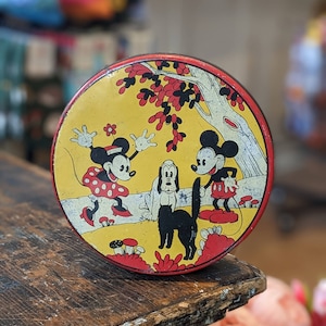 May include: Vintage tin lunchbox featuring Mickey Mouse, Minnie Mouse, and Pluto in a forest setting. The lunchbox is yellow with red accents and features a black and white dog.