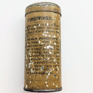 Puede incluir: Una lata vintage de metal con una superficie moteada de marr&oacute;n y blanco. La lata tiene una etiqueta negra con el texto "DIRECTIONS" e instrucciones para reparar pinchazos. El texto est&aacute; en negro con un contorno blanco.