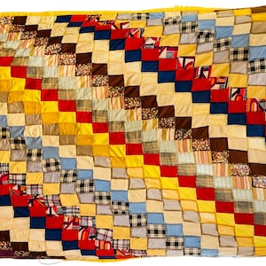 May include: A patchwork quilt with a diagonal pattern of squares in various colours, including yellow, red, blue, and brown.