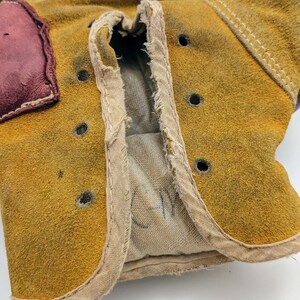 Puede incluir: Un par de guantes de boxeo de cuero marr&oacute;n con un exterior de gamuza beige. Los guantes tienen un forro blanco y una inscripci&oacute;n manuscrita que dice "CM".