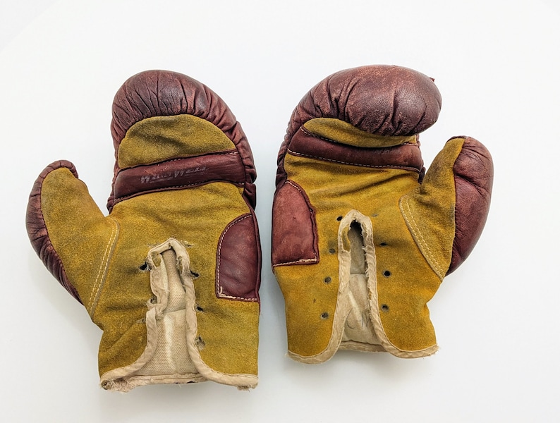 Puede incluir: Un par de guantes de boxeo vintage de cuero marr&oacute;n y gamuza amarilla. Los guantes tienen cordones y est&aacute;n desgastados.