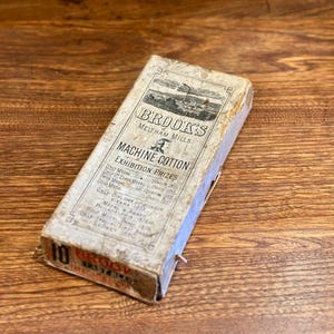 May include: A vintage box of Brooks Machine Cotton from Meltham Mills. The box lists exhibition prizes, including a gold medal, and mentions diplomas from Vienna 1873 and Philadelphia 1876.