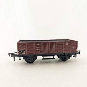 May include: A brown toy freight car with black wheels and a black undercarriage. The car has white lettering that reads "1205 0m 12" and "11350 kg 12t", and a black number "10" on the side. The car is on a white background.