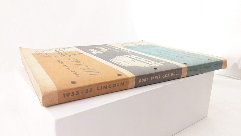 May include: A vintage 1953-55 Lincoln Body Parts Catalogue, March 1958, with a brown cover and the text "1953-55 Lincoln Body Parts Catalogue March 1958" printed on the spine.