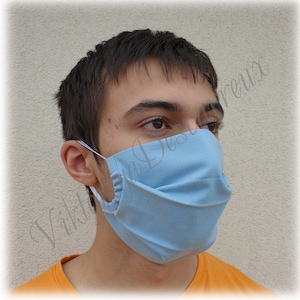 May include: A light blue face mask with pleats. The mask is made of a soft, breathable fabric and has elastic ear loops.
