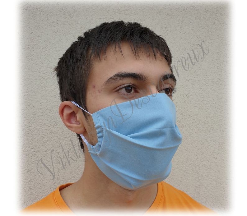 May include: A light blue face mask with pleats. The mask is made of a soft, breathable fabric and has elastic ear loops.