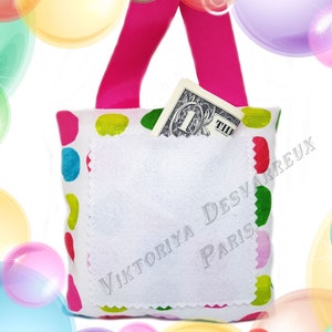 May include: A white fabric bag with a pink strap and a colorful polka dot pattern. The bag has a white pocket with the text "Viktoriya Desvarreux Paris" embroidered on it. A one dollar bill is tucked into the pocket.
