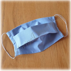 May include: A light blue pleated fabric face mask with white elastic ear loops.