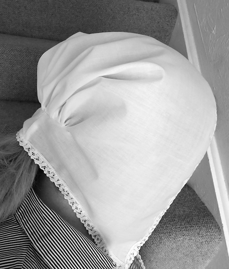 May include: A white cotton bonnet with lace trim. The bonnet is gathered at the top and has a simple, classic design.