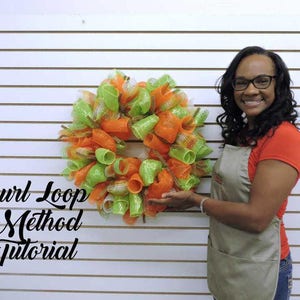 Può includere: Una donna dimostra il metodo del loop curl per realizzare una ghirlanda. La ghirlanda è realizzata con rete arancione e verde ed è esposta su uno sfondo di pannello di legno bianco. Il testo "Curl Loop Method Tutorial" è scritto in nero sul lato sinistro dell'immagine.