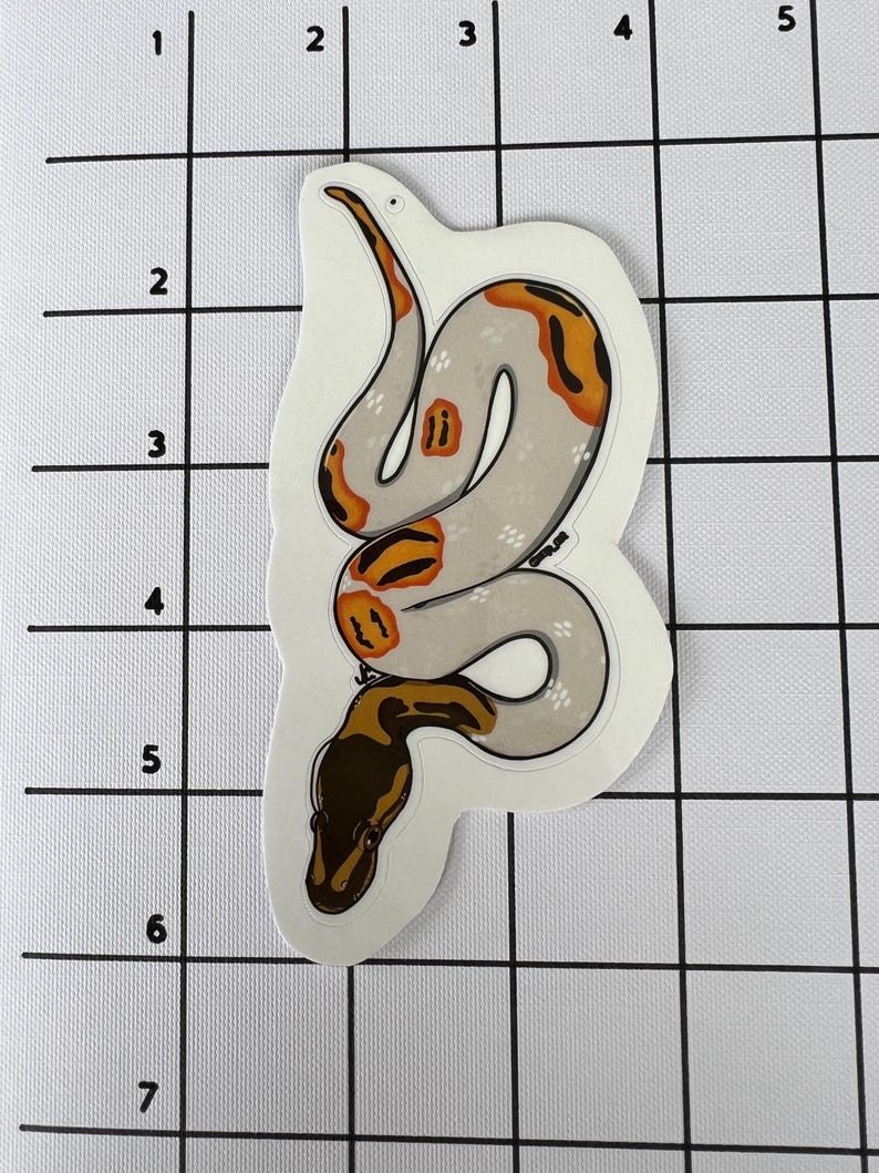 May include: A sticker depicting a stylized snake illustration. The snake has a light grey body with orange and brown markings. The snake's head is brown, and the sticker has a white border.