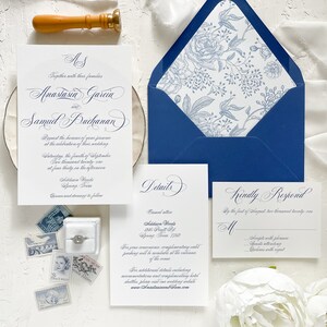 Puede incluir: Un conjunto de invitaciones de boda con un sobre azul y un forro floral blanco. La tarjeta de invitaci&oacute;n presenta un dise&ntilde;o floral azul marino y blanco con el texto "As Together with their families Anastasia Garcin and Samuel Buchanan Request the honor of your presence at the celebration of their wedding Saturday, the fourth of September Two thousand twenty-one at four thirty in the afternoon Addison Woods Spring Texas Dinner and dancing to follow". La tarjeta de detalles presenta el texto "Details Casual attire Addison Woods 45 Swift Rd Spring Texas 77318 For your convenience, complimentary valet parking will be available at the entrance of the venue For additional details including accommodations and complimentary hotel shuttles, please visit our wedding website www.AnastasiaandSam.com". La tarjeta RSVP presenta el texto "Kindly Respond By the first of August, two thousand twenty-one M Accept with pleasure Guests attending Decline with regret".