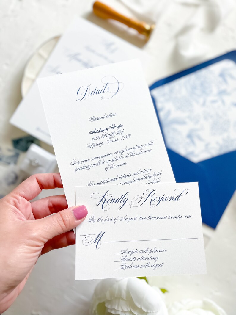 Puede incluir: Una tarjeta RSVP blanca con caligraf&iacute;a azul que dice "Kindly Respond" y "By the first of August, two thousand twenty-one". La tarjeta tiene tres l&iacute;neas para que los invitados indiquen su respuesta: "Accepts with pleasure", "Guests attending" y "Declines with regret".