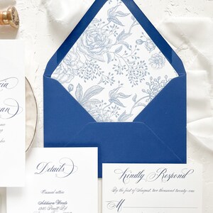 Puede incluir: Un sobre azul con un forro floral blanco. El sobre est&aacute; abierto y el interior es visible. El texto en el sobre dice "Kindly Respond" y "By the first of August, two thousand twenty-one".