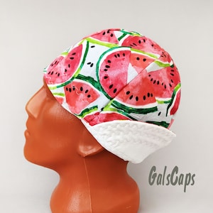 May include: A white and red patterned scrub cap with a watermelon print. The cap has a white brim and is made of cotton.