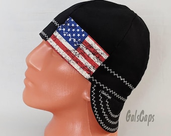 May include: Black welding cap with a distressed American flag design on the side. The cap has a white zig-zag stitch around the edge and the text "GalsCaps" is visible on the side.