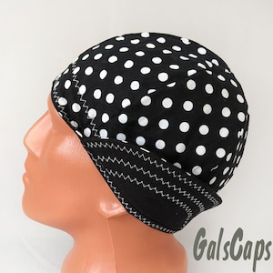 May include: A black and white polka dot cap with a black brim. The cap is made of cotton fabric and has a white stitching detail around the brim.