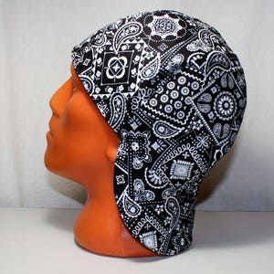 May include: Black and white paisley patterned welding cap with a long flap at the back.