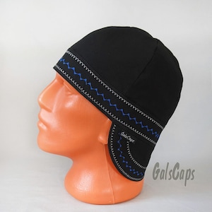 May include: Black cap with blue zigzag stitching along the brim and ear flaps. The cap is displayed on an orange mannequin head. The brand name "GalsCaps" is visible on the ear flap.