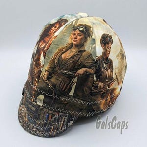 May include: A welding cap featuring a multi-panel design with a printed graphic of three individuals wearing steampunk-inspired attire and goggles. The cap includes white zigzag stitching along the seams and the text GalsCaps in the lower right corner.