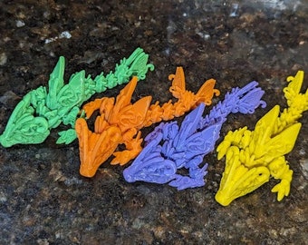 May include: Five 3D printed dragon figurines in various colors, including green, orange, purple, and yellow. The dragons are detailed with intricate scales and wings.