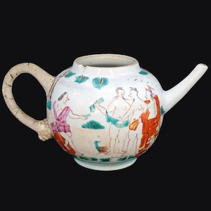 Puede incluir: Una tetera de cerámica blanca con cuerpo redondo, asa curva y pico largo. La tetera está decorada con una escena pintada de figuras en rosa, naranja y azul. El asa tiene un aspecto agrietado y envejecido.