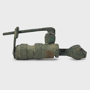 Könnte beinhalten: Eine weiße Keramiktasse mit schwarzem Henkel und dem Text "But First, Coffee" in fetter, schwarzer Schrift. Die Tasse steht vor einem verschwommenen Hintergrund, der eine gemütliche Umgebung suggeriert.