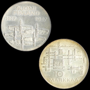 May include: Two silver Finnish coins on a black background. One coin has the text "SUOMI FINLAND 1917 1967" and an abstract design. The other coin has the text "10 MARKKA" and a geometric pattern.
