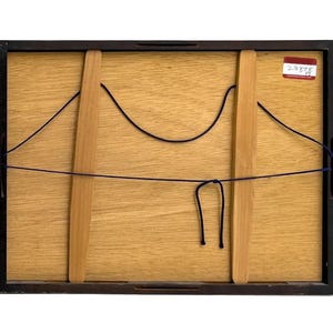 Op de afbeelding: De achterkant van een ingelijst kunstwerk, met een lichtbruin houten paneel met twee verticale houten steunen. Zwarte draad is over het paneel gespannen en een klein rood-wit label is zichtbaar in de rechterbovenhoek. Het frame is zwart.