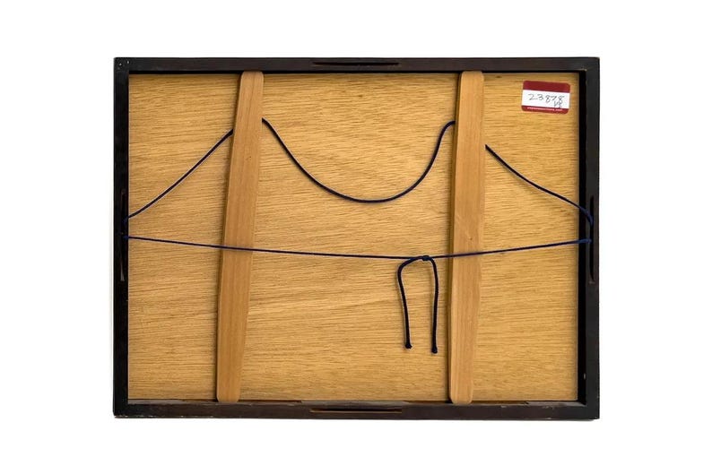 Op de afbeelding: De achterkant van een ingelijst kunstwerk, met een lichtbruin houten paneel met twee verticale houten steunen. Zwarte draad is over het paneel gespannen en een klein rood-wit label is zichtbaar in de rechterbovenhoek. Het frame is zwart.