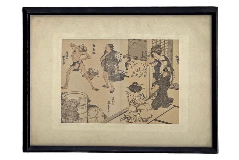 Op de afbeelding: Ingelijste zwart-wit Japanse houtsnede die een huiselijke sc&egrave;ne met figuren en dieren uitbeeldt. Het kunstwerk is geplaatst in een cr&egrave;mekleurige passe-partout en een zwarte houten lijst.