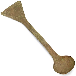 May include: A vintage bronze-colored tool with a triangular head and a rounded end. The tool has a long, slender handle and appears to be made of metal. The object is set against a white background.