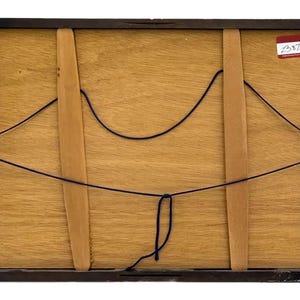May include: Back of a framed artwork. The frame is dark brown, and the backing is light brown wood. Two wooden supports are visible, held in place with dark blue string. A small sticker with text is in the upper right corner.