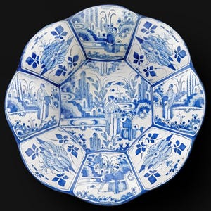 May include: A white and blue ceramic plate with a unique, scalloped edge. The plate features a detailed, hand-painted design with figures and landscapes in a classic blue and white color scheme. The plate's design is divided into several sections.
