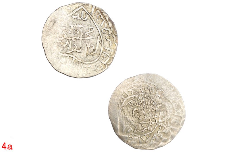 Puede incluir: Dos monedas antiguas de plata con intrincadas inscripciones &aacute;rabes. Las monedas circulares, ligeramente desgastadas, se presentan sobre un fondo blanco. Las detalladas inscripciones sugieren una importancia hist&oacute;rica.