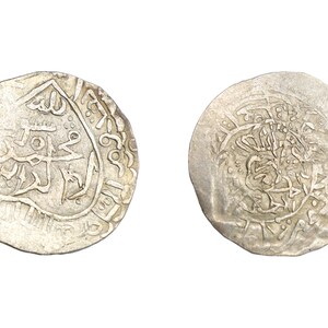 Puede incluir: Dos monedas antiguas de plata con intrincadas inscripciones y dise&ntilde;os &aacute;rabes. Las monedas circulares muestran signos de desgaste, lo que indica su antig&uuml;edad. Una moneda presenta caligraf&iacute;a detallada, la otra un patr&oacute;n complejo.