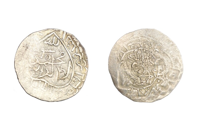 Puede incluir: Dos monedas antiguas de plata con intrincadas inscripciones y dise&ntilde;os &aacute;rabes. Las monedas circulares muestran signos de desgaste, lo que indica su antig&uuml;edad. Una moneda presenta caligraf&iacute;a detallada, la otra un patr&oacute;n complejo.