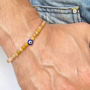 May include: A yellow and orange beaded bracelet with a blue evil eye charm.