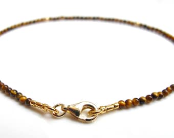 May include: A gold chain necklace with brown tiger's eye beads.