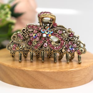 May include: A gold hair clip with a pink bow design and rhinestones.