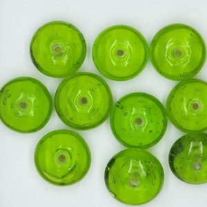 May include: Ten lime green glass beads with a hole in the center. The beads are round and have a slightly textured surface.