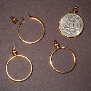 May include: Four gold-toned coin frames with a loop for hanging. The frames are designed to hold a quarter dollar coin.